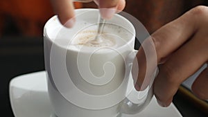 person hand stirring coffee with spoon.