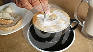 person hand stirring coffee with spoon.