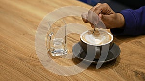 person hand stirring coffee with spoon.