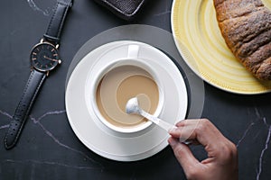 person hand stirring coffee with spoon.