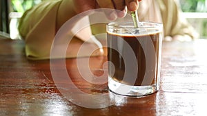 person hand stirring coffee with spoon.