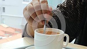 person hand stirring coffee with spoon.