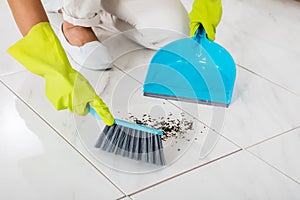 Person Hand Using Broom And Dustpan For Cleaning Floor