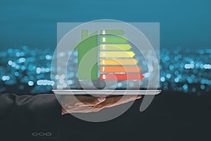 Person hand using tablet computer with house icon energy efficiency scale image on office desk