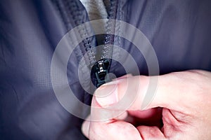 Person hand zipping up zipper on his jacket photo