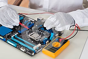 Person Hands Checking Motherboard With Multimeter