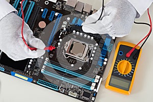 Person Hands Checking Motherboard With Multimeter