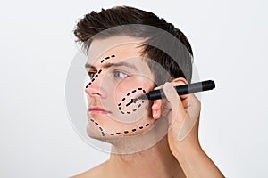 Person Hands Drawing Correction Lines On Male Face photo