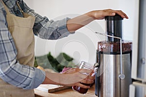 Person, hands and kitchen with juicer, blender or mixer for fruit, smoothie or nutrition at home. Closeup of