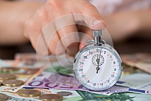 Person Hands With Stopwatch And Coins Over Banknote