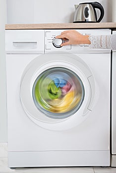 Person Hands Turning Button Of Washing Machine