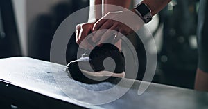 Person, hands and tying shoes at gym getting ready for workout, exercise or indoor training. Closeup of athlete tie shoe