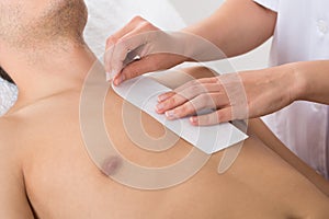 Person Hands Waxing Man's Chest