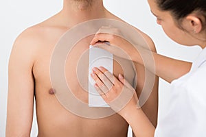 Person Hands Waxing Man's Chest