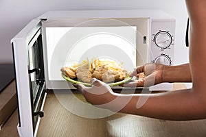 Person Heating Fried Food In Microwave Oven