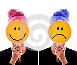 Person hiding her face behind happy and unhappy smileys