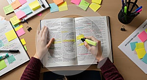 Person Highlighting Text in Open Book While Studying at Desk