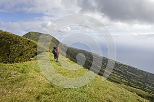 Person hiking along an old volcanic crater rim on São Jorge island in the Azores