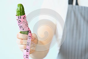 Person hold cucumber with measure tape around, diet and healthy and organic food