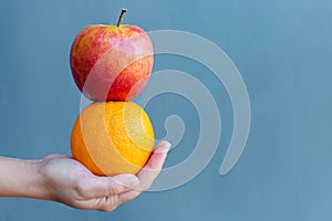 A person holding a apple and orange fruit. Healthy food diet