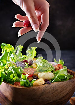 The person holding berries and put it in a salad