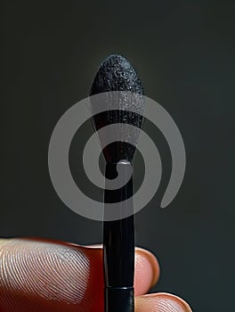 A person holding a black makeup brush