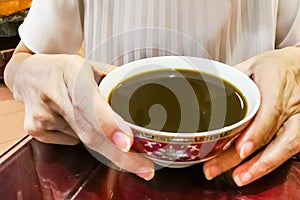 Person holding bowl of therapeutic Traditional Chinese Medicine