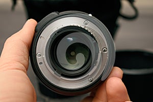 person holding camera lens and rear bayonet view of lens