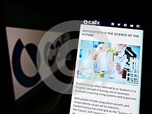 Person holding cellphone with website of Australian technology company Calix Limited on screen in front of logo.