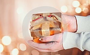 Person holding Christmas gift box over Xmas holiday background. Winter Holiday backdrop. Christmas and New Year decoration