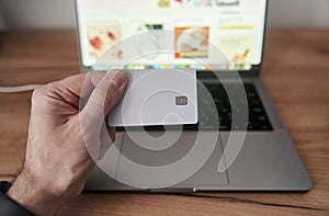 Person holds credit card in front of computer for online transaction