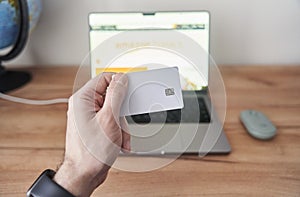 Person holds credit card in front of computer for online transaction