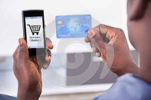 Person holding credit card and mobile phone