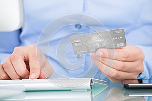 Person Holding Credit Card Using Computer