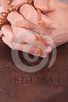 Person holding cross on bible