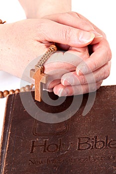 Person holding cross on bible