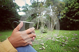 Closeup of woman sitting relax on park, hands holding cup of tea or coffee. photo