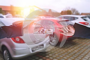 Person holding dollar money in the hands stands front car at modern showroom