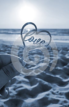 Person holding finger hand stick shape heart word Love background sea Blue color