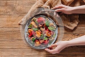 person holding fork and plate with salad with mussels, vegetables