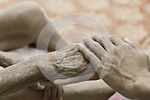 A person holding a hand An old woman lying in bed sick