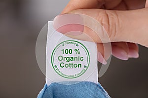 Person Holding Label Showing 100 Percent Organic Cotton