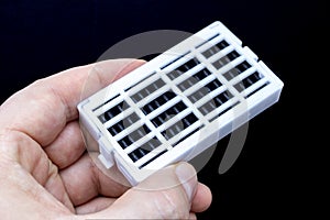 A person holding on the left side a Refrigerator Air Filter Replacement for kitchen Fridges upside down. Fresh Flow Fridge