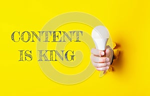 A person holding a light bulb with the words content is king written behind them