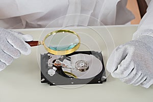 Person Holding Magnifying Glass Over Harddisk