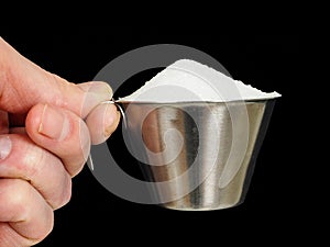 Person holding a measuring cup of sugar