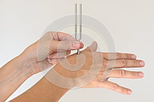 Person holding metal tuning fork against hand