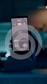 Person holding mobile with high tech application turning on lights
