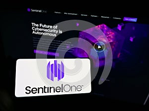 Person holding mobile phone with logo of cybersecurity firm Sentinel Labs Inc. (SentinelOne) on screen with web page.