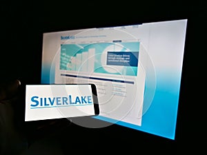 Person holding mobile phone with logo of US private equity investment company Silver Lake Technology Management on display.